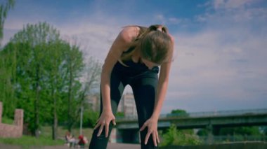 Genç bir kadın nehir kenarında koşup koştuktan sonra dinleniyor. Sabah koşusundan sonra dinlenen kadın portresi. Koşu yaşam tarzı sağlıklı yaşam tarzı.