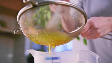 Kadın aşçı süzgeçten geçen yumurta sarısı süzüyor. Altın sıvıyı ince bir ağ süzgecinden geçirip mutfak ortamında ölçü kabına sokan biri. Elle aşçılık tekniği..