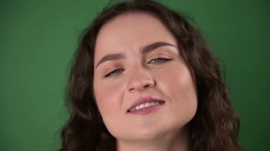 Yeşil arka planda sakin ve mutlu genç bir kadın. Cepheden mutlu bir kadının yeşil bir arka planda anahtarlama ya da birleştirme için yakın plan çekimi. Stüdyo çekimi
