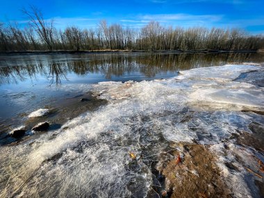Kasım ayında Manitowoc Nehri 'nde sonbahar buzları oluşur ve Manitowoc, Wisconsin' de arka planda bir orman bulunur..
