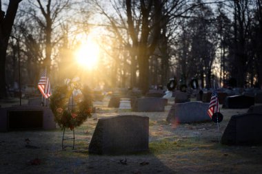 Wisconsin mezarlığında güneş bayraklar ve Noel çelenkleri üzerinde yükseliyor..