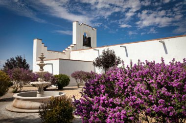 Purple flowers line the side of the Socorro Mission, on the El Paso Mission Trail, in Socorro, Texas.