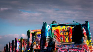 On historic Route 66, the Cadillac Ranch stands near Amarillo, Texas as a public art exhibition of ten Cadillacs buried at the same angle as the pyramids at Giza.  Visitors are also encouraged to spray paint the cars.