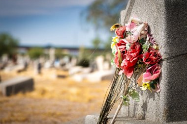 Yapay çiçekler, güneş ve sıcaktan harap olmuş, El Paso, Teksas 'taki Concordia Mezarlığı' nda bir mezar taşında..