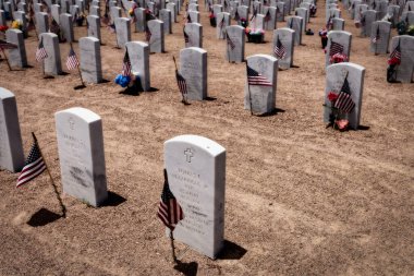 El Paso, Teksas 'taki Fort Bliss Ulusal Mezarlığı' nda Amerikan askerlerinin mezarlarında bayrak sallayan güneşli bir Anma Günü..