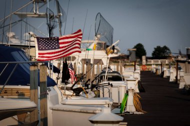 Güneş, Ludington, Michigan limanındaki bir teknenin arkasında bir Amerikan bayrağı üzerinde yükseliyor..