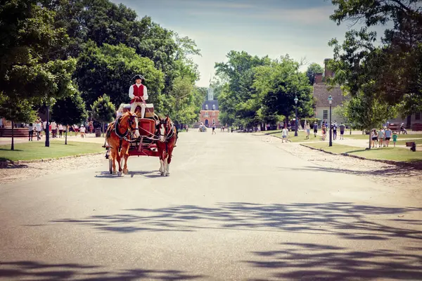 stock image A horse-drawn carriage travels the tourist filled streets of Colonial Williamsburg, Virginia.