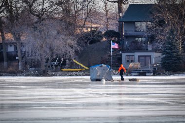 Bir adam, Manitowoc, Wisconsin yakınlarındaki İngiliz Gölü 'ndeki gecekondusuna buz balıkçılığı malzemeleriyle kızağını sürüklüyor..