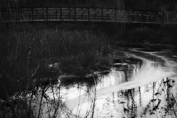 Silver Creek gökyüzünü yansıtır ve Manitowoc, Wisconsin 'deki Silver Lake yakınlarındaki yaya köprüsünün altından geçer..