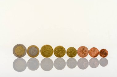 Beyaz bir masanın üzerinde duran bir dizi euro sikkesi