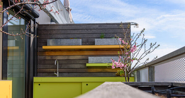 Beautiful roof terrace with wooden floor with yellow and green planters for urban gardening and flowering trees