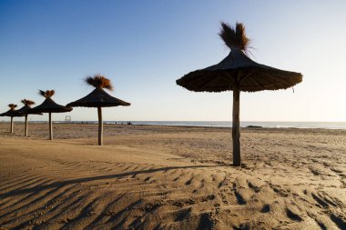 Perspektifte saman şemsiyeli plaj. Sahilde güzel bir yaz sabahı. Mar Azul, Arjantin.