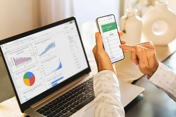 Adam cep telefonu ve dizüstü bilgisayarda Sheets uygulaması kullanıyor. Google Çalışma Alanı, çevrimiçi dijital üretkenlik araçları. ROSARIO, ARJANTINA - 20 Şubat 2024.