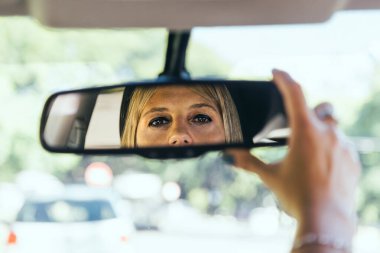 Sürücü kadın arabasının dikiz aynasını ayarlıyor..