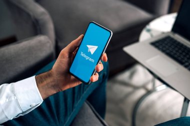 Cep telefonlu bir adam ekranda telgraf uygulamasını gösteriyor. İş yerinde dizüstü bilgisayarı ve elinde akıllı telefonu olan bir adam. ROSARIO, ARJANTINA - 3 Temmuz 2024.