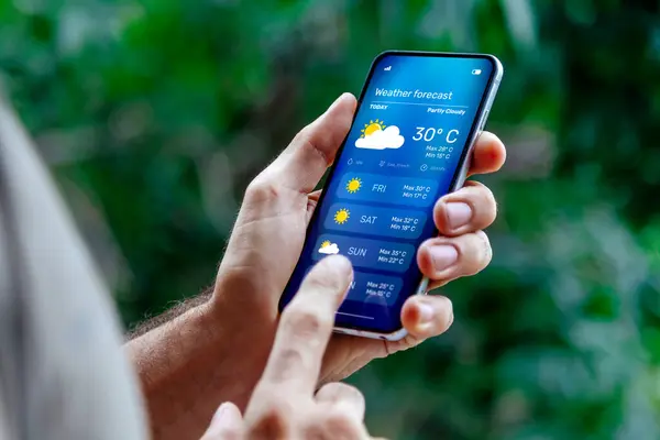 Dışarıdaki adam cep telefonundan hava tahminlerini kontrol ediyor..