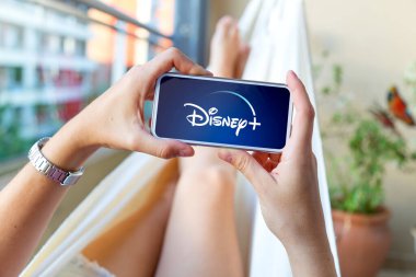 Disney ve logoti ekranda olan bir cep telefonu kullanan genç bir kadın. Canlı video ve eğlence uygulaması. Rosario, Arjantin - 16 Ekim 2024