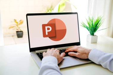 Microsoft Office PowerPoint 'in logosunu ekranda gösteren bir dizüstü bilgisayar kullanan adam. Güç noktası bir sunum programıdır. ROSARIO, ARJANTINA - 18 Ekim 2024.