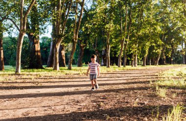 Küçük çocuk gün batımında doğada tek başına yürüyor..