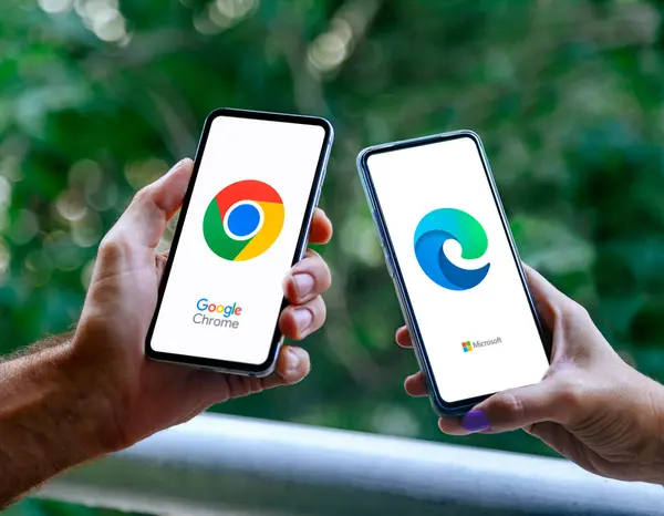 Birinde krom tarayıcıyı, diğerinde mikrosoft kenarını gösteren cep telefonlu iki kişinin elleri. Rosario, Arjantin - 8 Mart 2025.