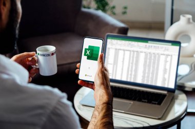 Ekranda Microsoft Excel 'in logosunu gösteren bir cep telefonu kullanan adam. Hesaplama, formüller ve verimlilik için hesap tablosu yazılımı. ROSARIO, ARJANTINA - 5 Nisan 2025.