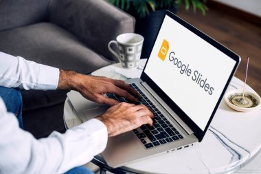 Google Slides 'in logosunu ekranda gösteren bir dizüstü bilgisayar kullanan adam. Slaytlar çevrimiçi bir sunum uygulaması. ROSARIO, ARJANTINA - 20 Nisan 2025.