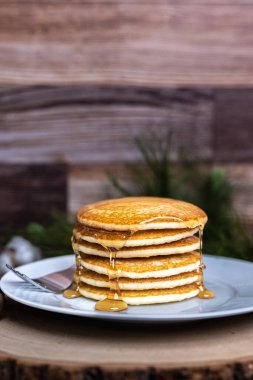 Bir ahşap zemin üzerine çatal ve şurup dökülmüş büyük bir tabak krep..