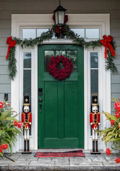 Christmas gree front door of a house home decorated for Christmas with a wreath and garland and two nutcrackers.