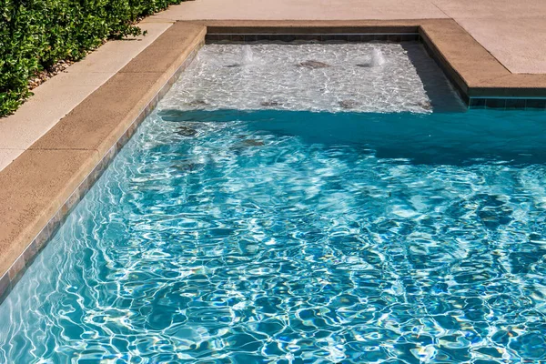 Stock image A rectangular new swimming pool with tan concrete edges in the fenced backyard of a new construction house.