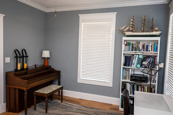 Home music room for students with a wood piano and blue gray walls.