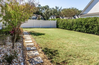 A landscaped small side yard of a new construction house with a young tree planted.