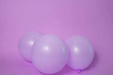A set of purple birthday party celebration balloons on a plain background with copy space.