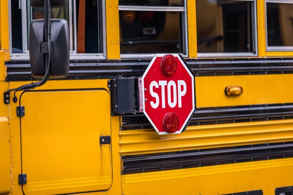 A close up of a yellow orange school bus with a red stop sign for back to school.