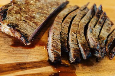sliced tender flank steak on a wood cutting board