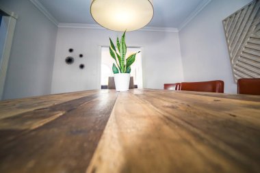 Lekeli ahşap yemek masasının tepesinde bir ev bitkisi var..