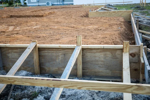 The beginning of a new construction build in a neighborhood with the foundation poured, dirt added and the wood based began.
