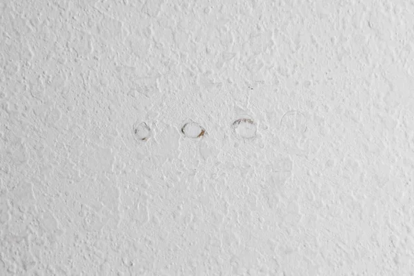 一种带有三个螺钉孔的稍带纹理的白色墙壁 这些孔已经被填满 正在等待涂漆以隐藏它们 — 图库照片