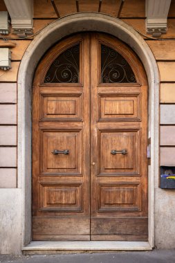 Roma, İtalya 'da bir apartmanın çift katlı, eski, koyu renkli, ahşap kapıları..