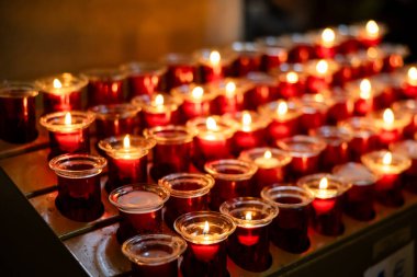 Roma 'daki koyu bir Avrupa Katolik kilisesinde yakılan kırmızı dua mumları. İtalya, Tanrı' dan ya da azizden bir lütuf bekliyor..