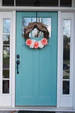 A spring floral wreath on a light blue aqua front door of a house home. clipart
