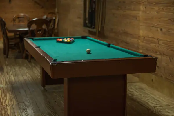 A pool table in a rustic cabin that is all set up and ready to play.