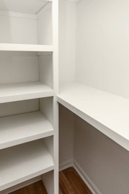 Eski bir evde ahşap rafları olan içi beyaz, katı ahşap bir dolap..