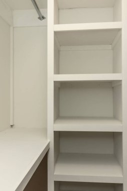 Eski bir evde ahşap rafları olan içi beyaz, katı ahşap bir dolap..