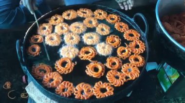 Hindistan 'da popüler olan Jalebi' nin kuru alüminyum bir tavada yakın plan fotoğrafı. Jalebi turuncu renktedir ve bol yağda kızartılmış hamur ve şeker şurubundan yapılır. Yüksek kalite 4K görüntü.