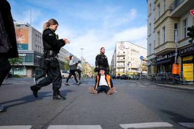 Berlin, Almanya - 24 Nisan 2023: Son Nesil grubundan protestocular sokakta oturup Berlin, Hermannplatz 'da trafiği engelliyor. Yüksek kalite fotoğraf