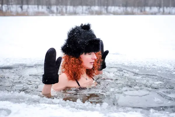 Winter swimming. Woman in frozen lake ice hole. Swimmers wellness in icy water. How to swim in cold water. Beautiful young female in frozen lake. High quality photo