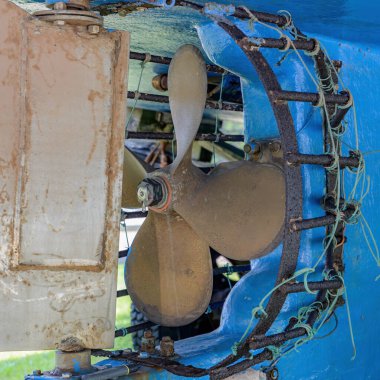 A closeup view of the propeller on a fishing boat with a rusty metal shroud. The shroud helps prevent rope etc from getting caught in the propeller. clipart