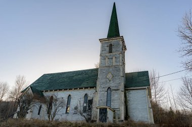 Alacakaranlıkta terk edilmiş eski bir kilise. Kilise kötü durumda ve güneş onun arkasında batıyor..