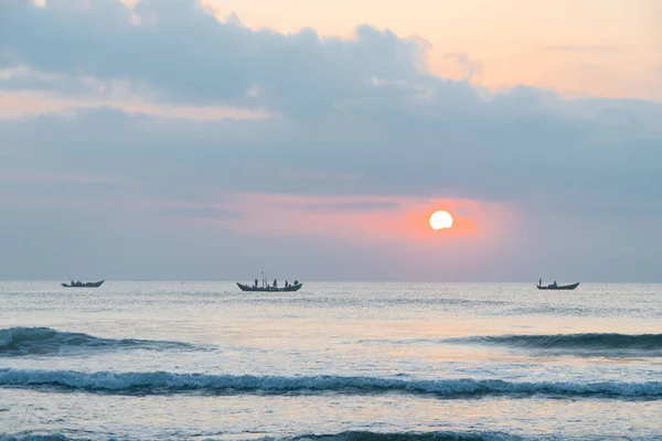 stock image Landscape of small fishing boats of Vietnamese fishermen fishing at dawn in the sea, with rising sun, clouds and sky. Seascape at sunrise and sunset in beautiful yellow and orange.