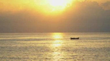 Şafakta deniz manzarası, parlak sarı güneş ışığı ve oradan geçen Vietnamlı balıkçı tekneleri. 4k video deniz manzarası gün doğumu ve gün batımı.